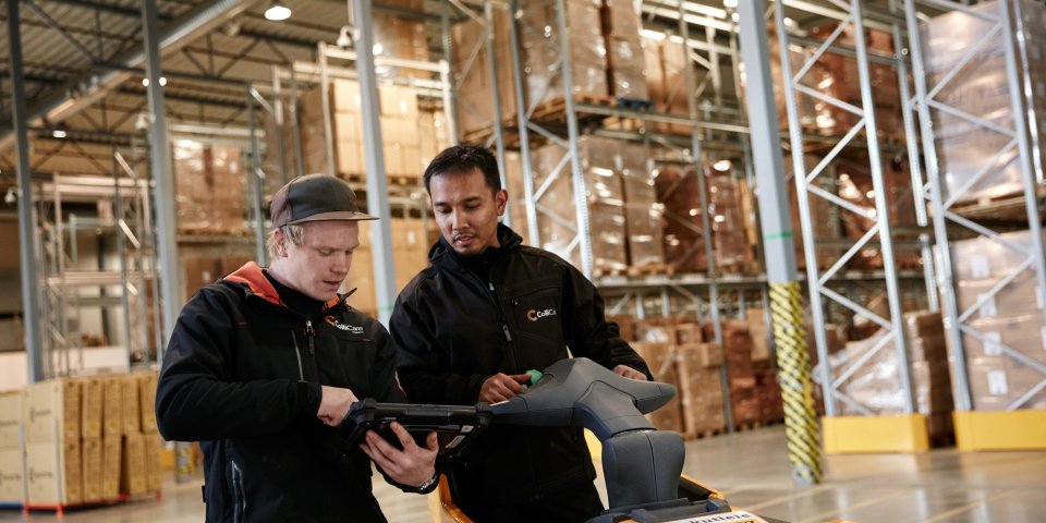 Two employees in branded clothes having a conversation in the storage surrounded by goods