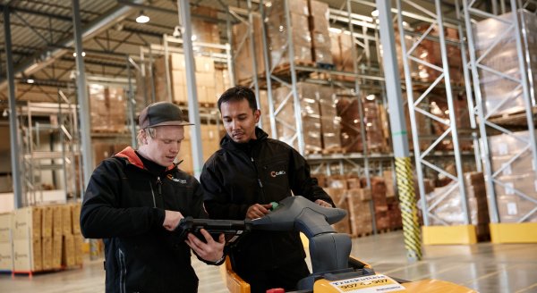 Two employees in branded clothes having a conversation in the storage surrounded by goods